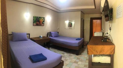 a hotel room with two beds and a table and a desk at วังอินธารา รีสอร์ท (Wangintara Resort) in Phitsanulok