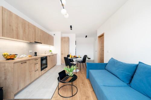 a living room with a blue couch and a kitchen at Komfortowe Apartamenty z Garażem na Milionowej in Łódź