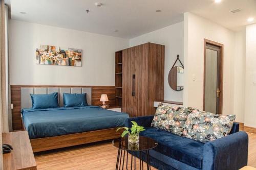 een slaapkamer met een blauw bed en een bank bij Laurel Da Nang Apartment in Da Nang