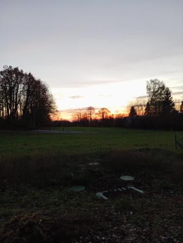 a field with the sunset in the background at La p'tite maison bois du hérisson in Ménétrux-en-Joux