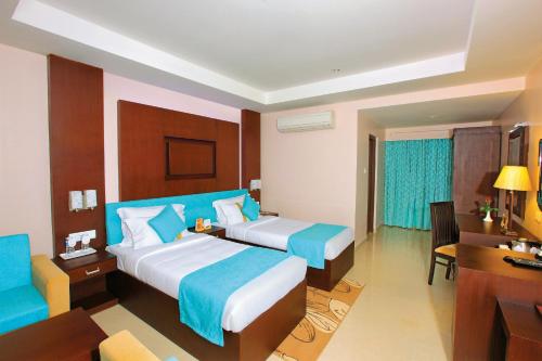Habitación de hotel con 2 camas y escritorio en HOTEL SRIVATSA REGENCY, en Pudunagaram