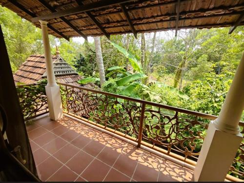 a balcony of a house with a view of the forest at Mandaram villas in Mararikulam