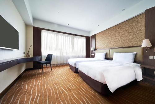 a hotel room with two beds and a television at ILLUME Taipei in Taipei