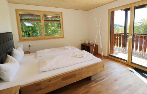 a bedroom with a large white bed and a balcony at Tannenhof Fischbach - Fewo 6 "Karpfen" - Schluchsee, 2 Schlafzimmer, E-Auto Ladestation in Schluchsee