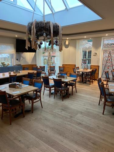 een eetkamer met tafels en stoelen en een groot dakraam bij Hotel Zum Großen Krug in Wirdum