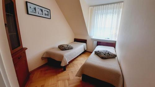 2 Betten in einem kleinen Zimmer mit Fenster in der Unterkunft Villa Krystyna in Dźwirzyno