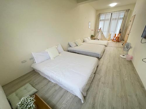 路邊覓宿 في Guilin: سريرين في غرفة بجدران بيضاء وأرضية خشبية