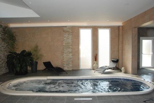 a large bath tub in a room with two chairs at Hotel De France in Pontorson