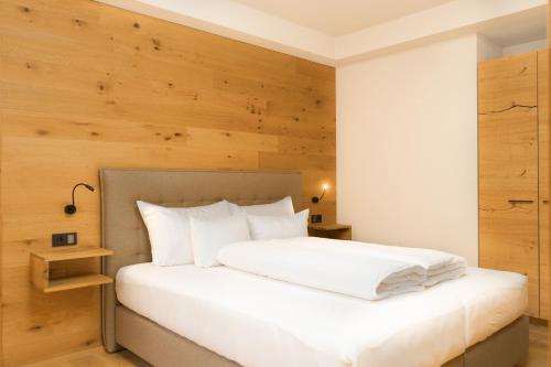 a bedroom with a white bed with a wooden wall at Heimat 1495m Appartement TYP 4 in Schröcken