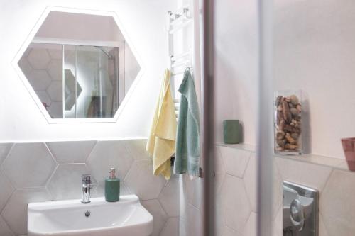 een witte badkamer met een wastafel en een spiegel bij Seek and Hide - Csilla's Tiny Hideaway in Braşov