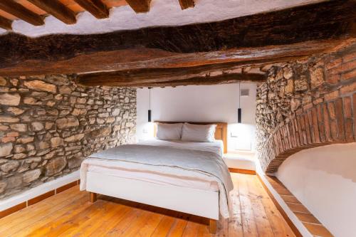 a bedroom with a bed in a stone wall at Affittacamere La Rocca Campiglia in Campiglia Marittima