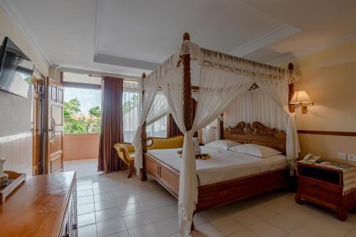 a bedroom with a canopy bed in a room at Palm Beach Hotel Bali in Kuta