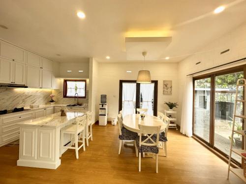 a kitchen with a white table and chairs and a table and a counter at Villa Putih Le Cordon in Bandung