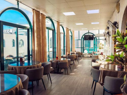 un restaurant avec des tables, des chaises et des fenêtres dans l'établissement Al Yasmeen Hotel, à Naplouse