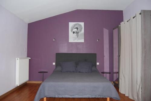 a bedroom with a purple wall with a bed at Les Goullans in Grazac