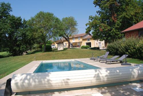 einen Pool mit zwei Liegestühlen neben einem Haus in der Unterkunft Les Goullans in Grazac
