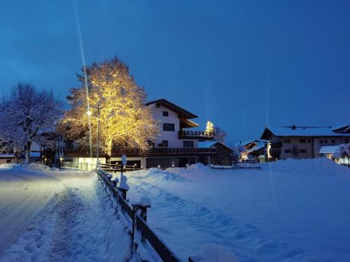 a snow covered yard at night with a building at Postgasthof Fischerwirt in Walchsee