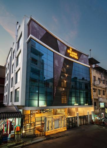 a large building with glass windows on a street at Hotel Vilvah in Coimbatore