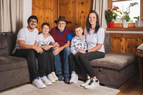 a family sitting on a couch posing for a picture at Elslerhof in Dobbiaco