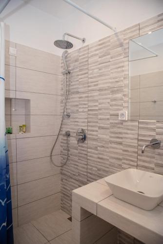 a bathroom with a shower and a white sink at Adonis Hotel Naxos in Apollon