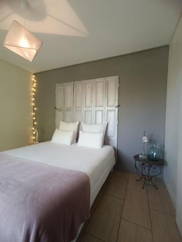 une chambre avec un grand lit blanc et une table dans l'établissement Les Ricochets - Maison d'hôtes, à Saint-Denis-lès-Martel