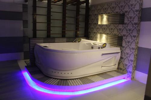 SEASHELLINN HOTEL في كراتشي: حوض أبيض في حمام مع أضواء أرجوانية