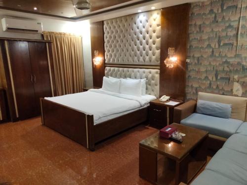 um quarto de hotel com uma cama e um sofá em SEASHELLINN HOTEL em Karachi