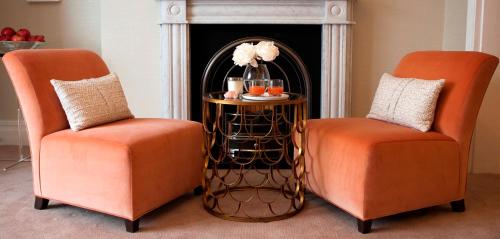 two orange chairs sitting next to a table with a side table at The Charm Brighton Boutique Hotel & Spa in Brighton & Hove