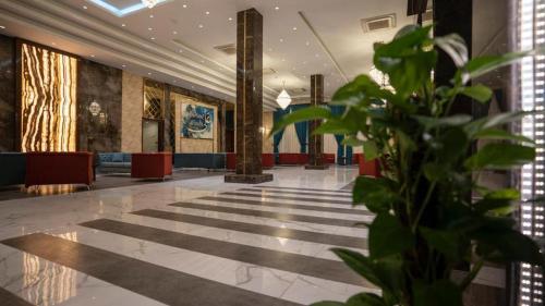 a lobby with a plant in the middle of it at Jar ALAmer Hotel in An Najaf