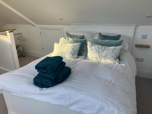 a white bed with blue sheets and pillows at Kittiwake - Outstanding River Views in Dartmouth