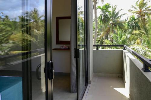 a glass door leading to a balcony with palm trees at Hidden Heaven in Dickwella