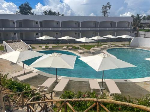 a pool with umbrellas and chairs and a building at AHG Lion Beach Resort in Watamu