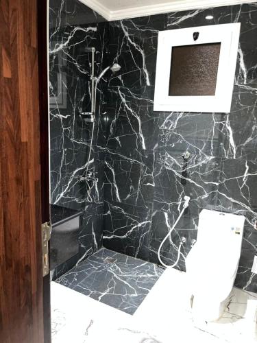 a bathroom with a black marble wall with a toilet at Maset Al Masem Apartments Units in Al Khobar