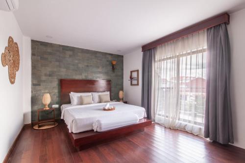 a bedroom with a bed and a large window at Angkor Eden Boutique Hotel in Siem Reap
