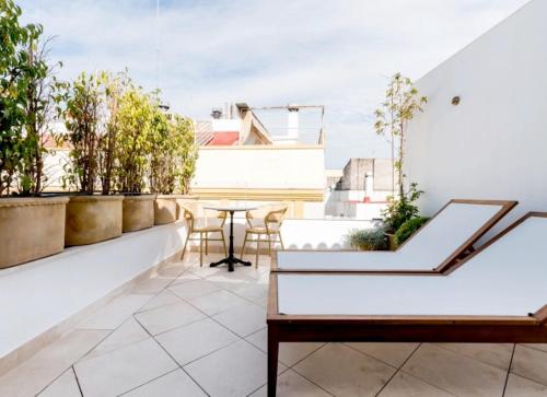 um apartamento com uma varanda com uma mesa e cadeiras em The Honest Hotel em Sevilha