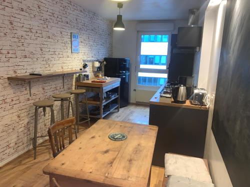 una cocina con mesa de madera y taburetes de bar en Appartement cosy, en Lyon