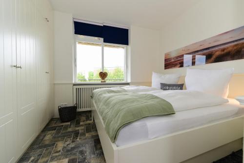 een slaapkamer met een groot wit bed en een raam bij Haus Bi de Wyk D9B in Wyk auf Föhr