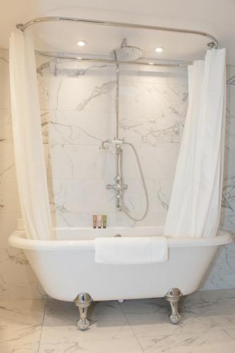 a white bath tub in a bathroom with marble walls at The Charm Brighton Boutique Hotel & Spa in Brighton & Hove