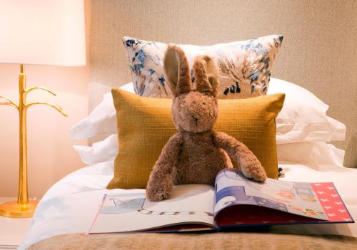 a stuffed rabbit sitting on a bed reading a book at The Charm Brighton Boutique Hotel & Spa in Brighton & Hove