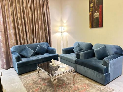 a living room with two blue couches and a table at Maset Al Masem Apartments Units in Al Khobar