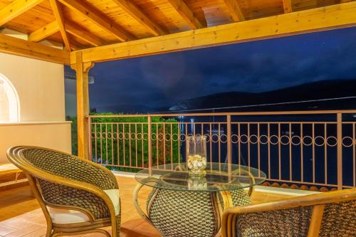 a glass table and two chairs on a balcony at Villa Pasithea in Korfos