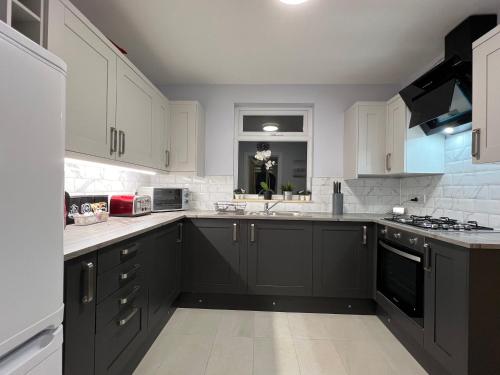 a kitchen with white cabinets and black appliances at Immaculate Newly Refurbished 4 Bed House in Nottingham