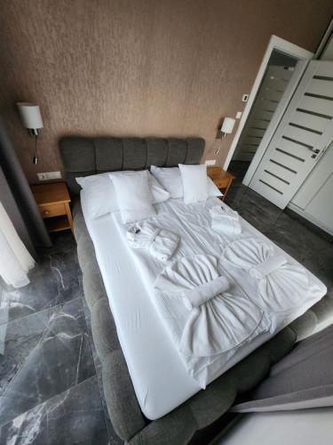 a large white bed with white sheets and pillows at Flavius Spa Residence in Hévíz