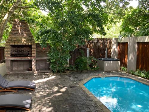un patio trasero con piscina y chimenea en Turaco Guest House, en St Lucia