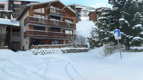 um edifício coberto de neve com um sinal em frente em Studio douillet aux deux Alpes em Les Deux Alpes