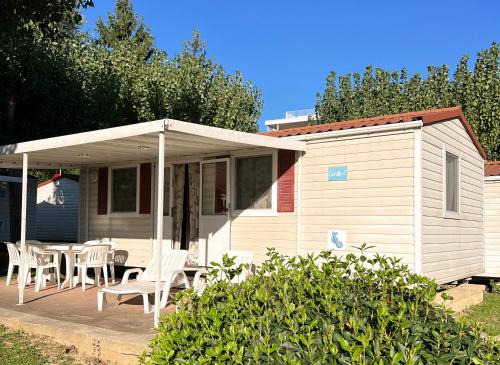 a white house with a table and chairs on a porch at San Benedetto Camping Relais in Peschiera del Garda