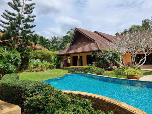a house with a swimming pool in front of a yard at Baan Zoe Villa in Ao Nang Beach