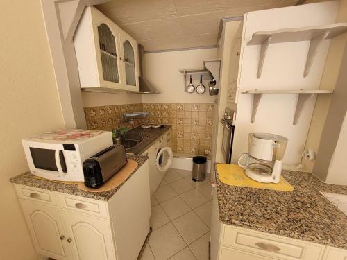 une petite cuisine avec un comptoir et un micro-ondes dans l'établissement Charmant Appart 4 Pers Proche Mer avec Terrasse et Parking, Stella - FR-1-672-30, à Cucq