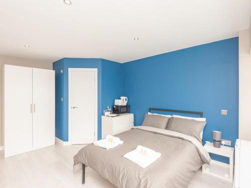 a bedroom with blue walls and a bed with two towels at Pass the Keys Burnley Central Hub Stylish Stay in Burnley