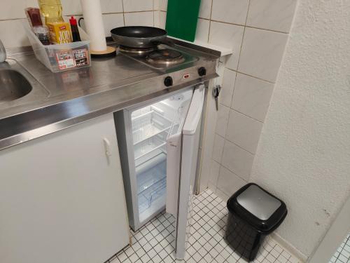 Elle comprend une petite cuisine équipée d'un réfrigérateur ouvert et d'un évier. dans l'établissement Ferienwohnung in Köln1901, à Cologne